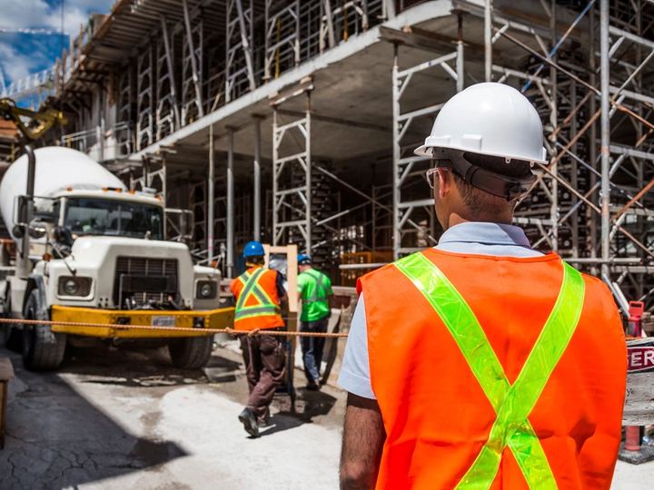 Bouwplaats met medewerkers in fluohesje en veiligheidshelm
